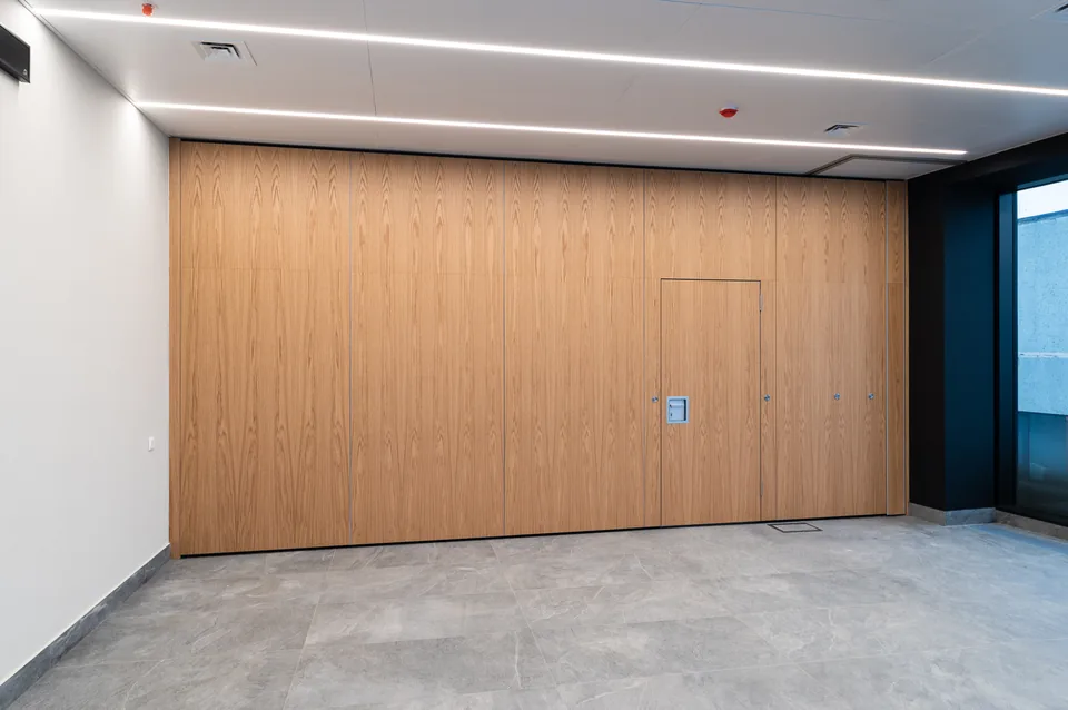 Oak-veneered operable wall with an integrated pass door
